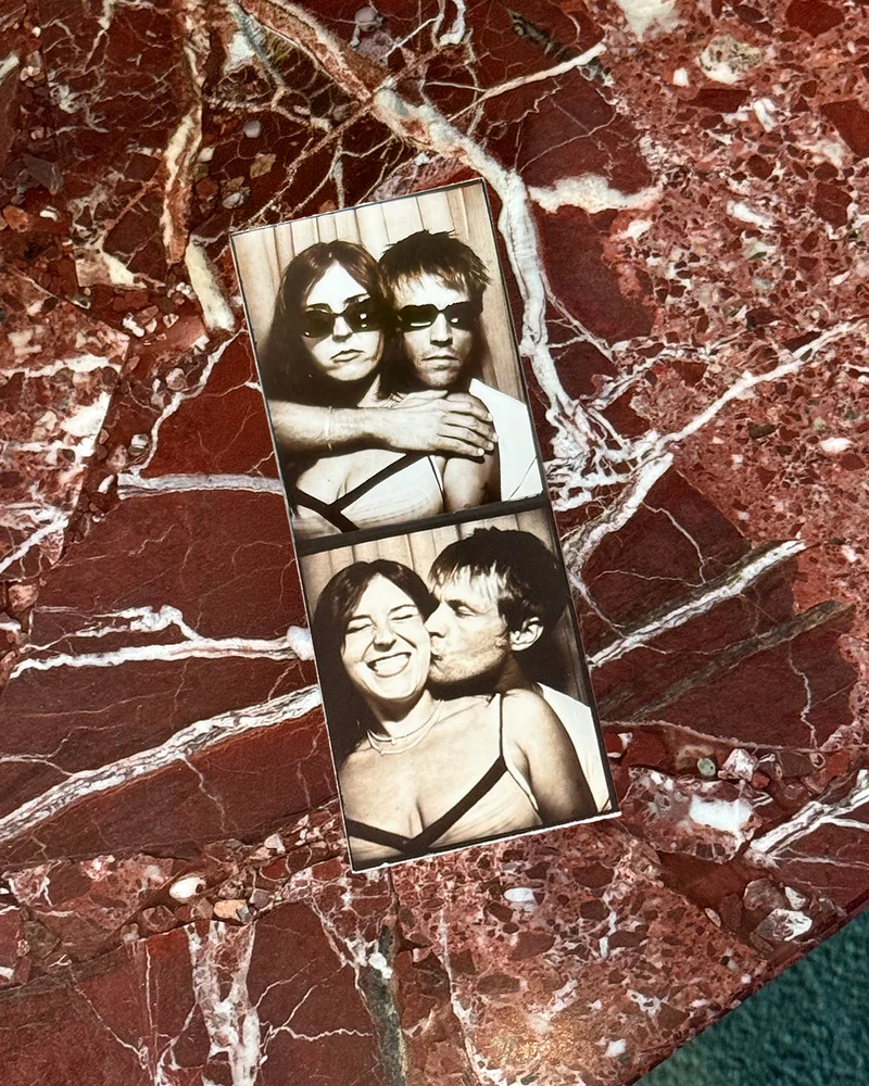 A two-frame sepia photo-booth strip of Amanda and Brad resting on red marble